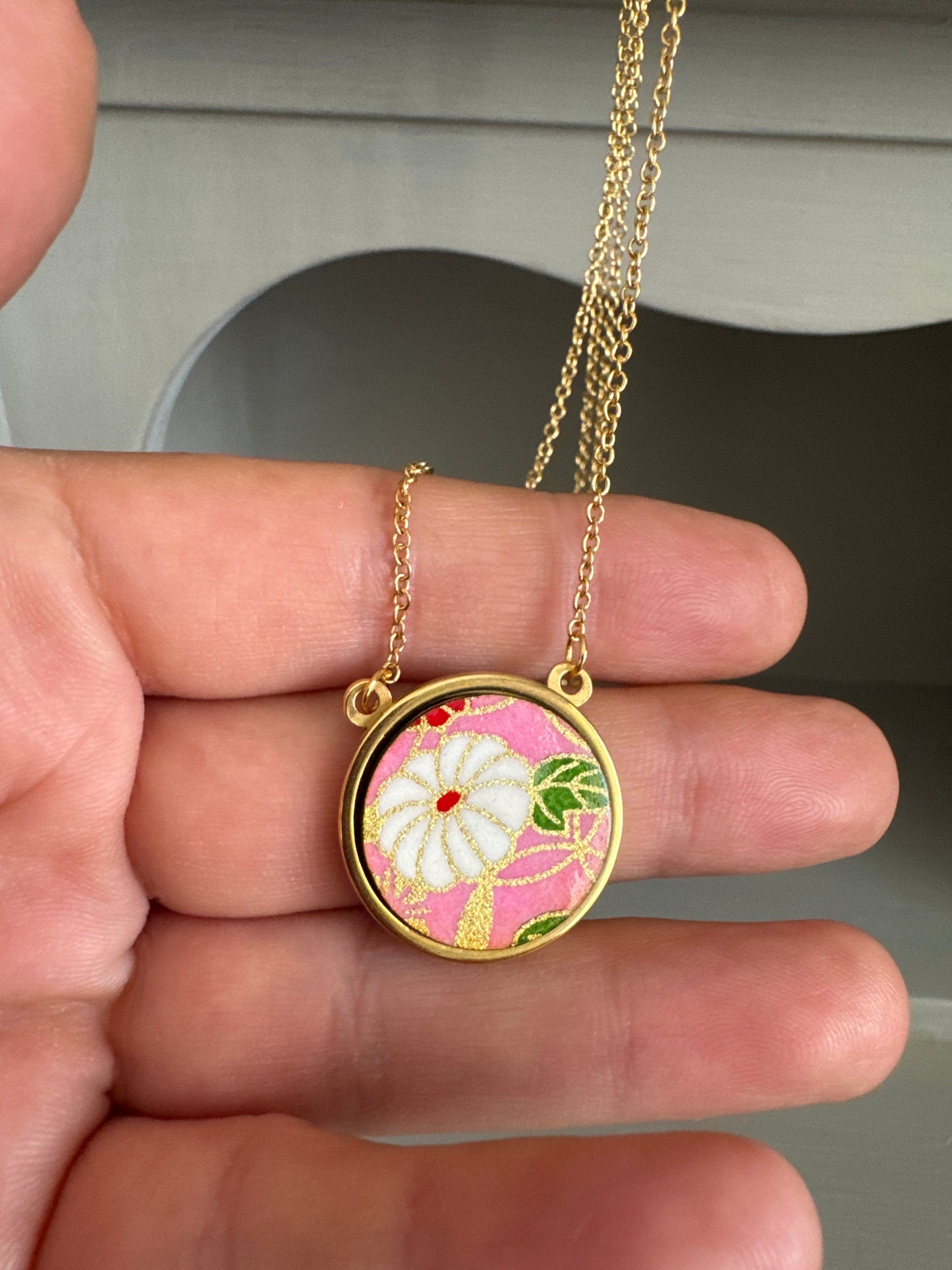Collana regolabile con ciondolo floreale su fondo rosa