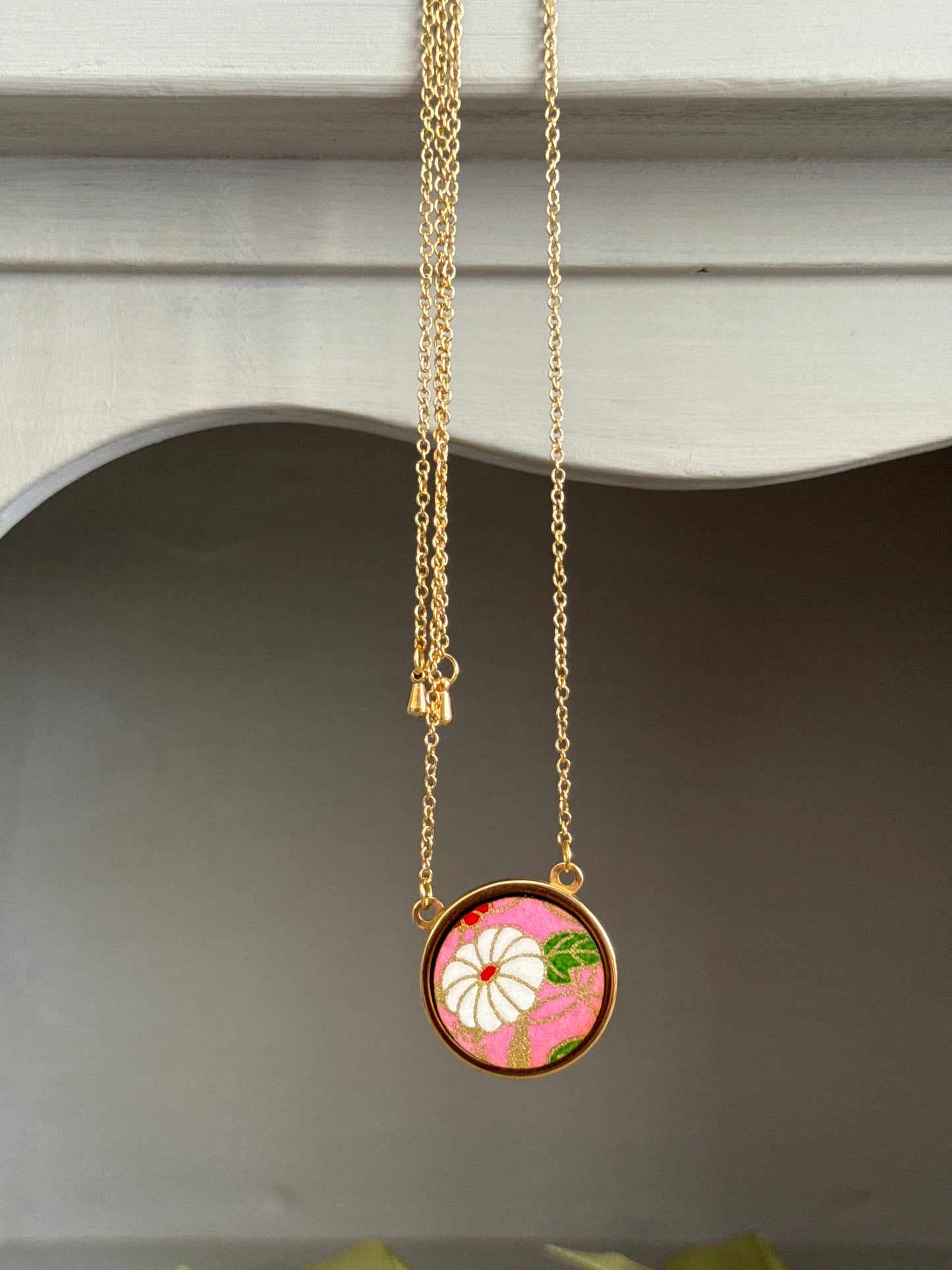 Collana regolabile con ciondolo floreale su fondo rosa